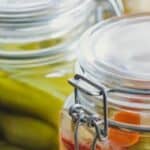 Pickles in glass jars on a wooden table.