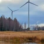 Wind turbines in a field next to a body of water.