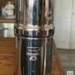 A stainless steel water filter sitting on top of a wooden table.
