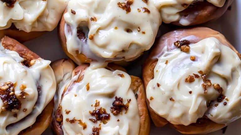 Close-up of cinnamon rolls topped with creamy icing and small bits of chopped nuts.