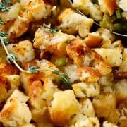 A dish of baked bread stuffing with herbs, featuring golden-brown bread cubes in a blue baking dish.