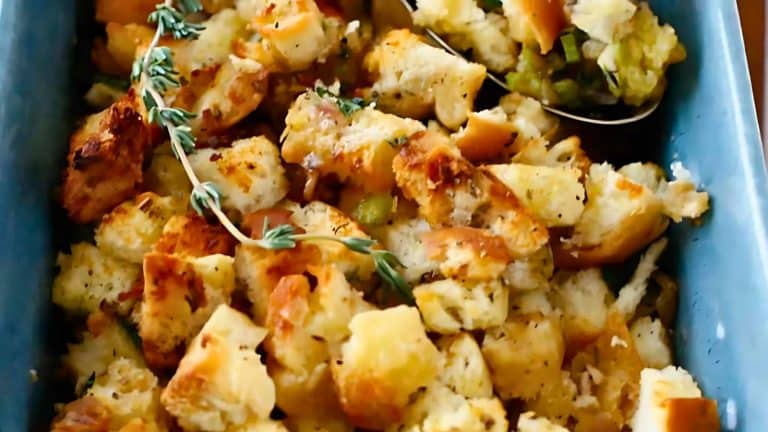 A dish of baked bread stuffing with herbs, featuring golden-brown bread cubes in a blue baking dish.