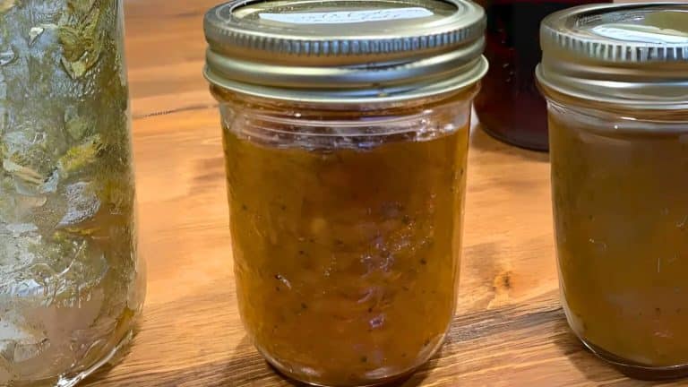 Three jars of homemade preserves are placed on a wooden table.