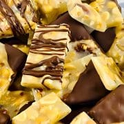 A close-up of assorted chocolate and nut bars, some drizzled with dark chocolate, on a checkered surface.