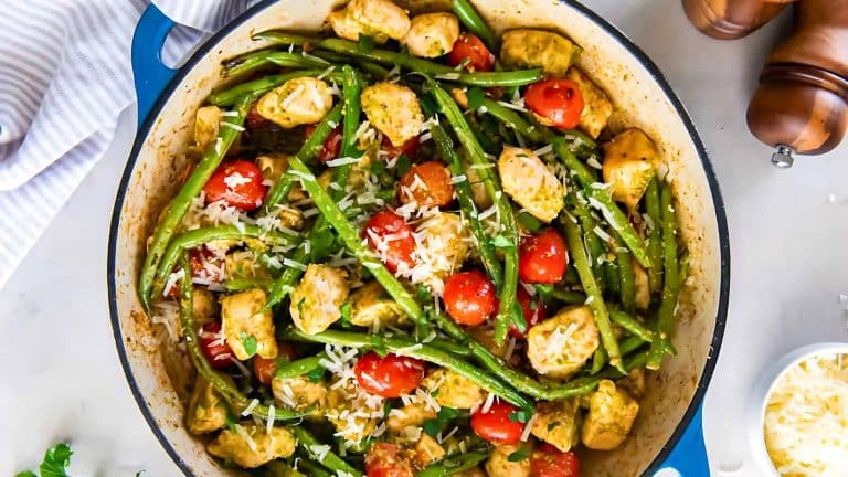 A pan of chicken with green beans, cherry tomatoes, and grated cheese on top.
