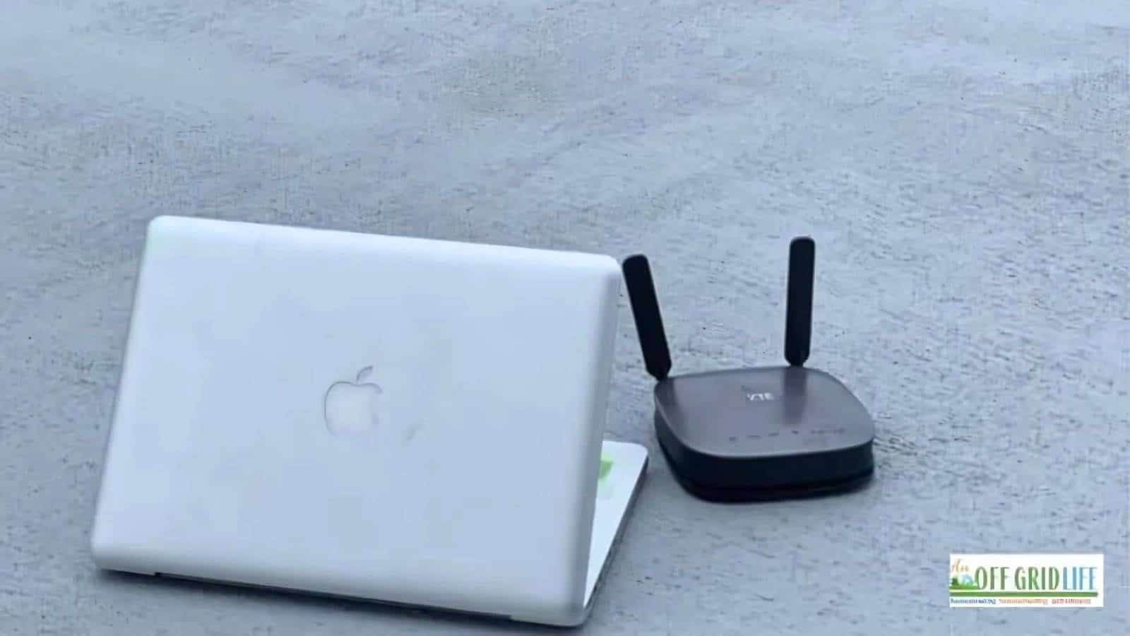 A closed laptop and a Wi-Fi router with two antennas are placed on a flat surface next to a logo reading "Off Grid Life.