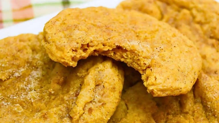 Close-up of several pumpkin cookies stacked, with one cookie on top having a bite taken out of it.