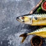 a picture of two smoked fish on a platter with a grey background