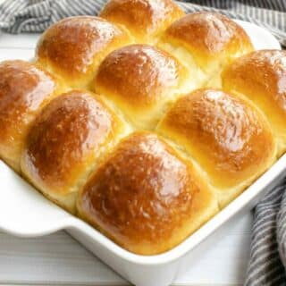 Condensed Milk Dinner Rolls in a baking dish on a wooden table.