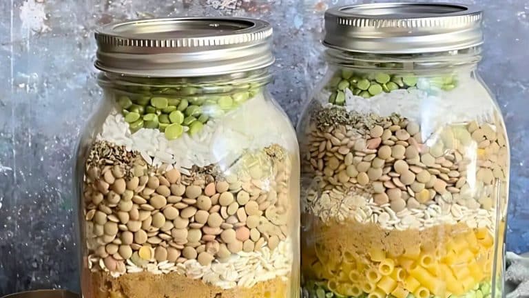 Two jars filled with layered ingredients including lentils, split peas, pasta, and spices, against a textured background.