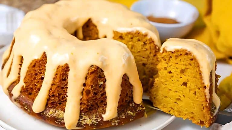 A glazed bundt cake with a slice cut out, revealing a moist, golden interior.