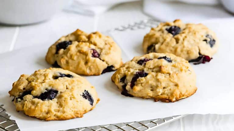 Four blueberry scones on a cooling rack lined with parchment paper.