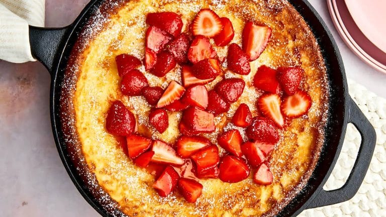 Skillet pancake topped with sliced strawberries and a dusting of powdered sugar.