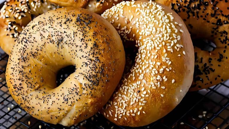 Two bagels on a cooling rack, one with poppy seeds and the other with sesame seeds.