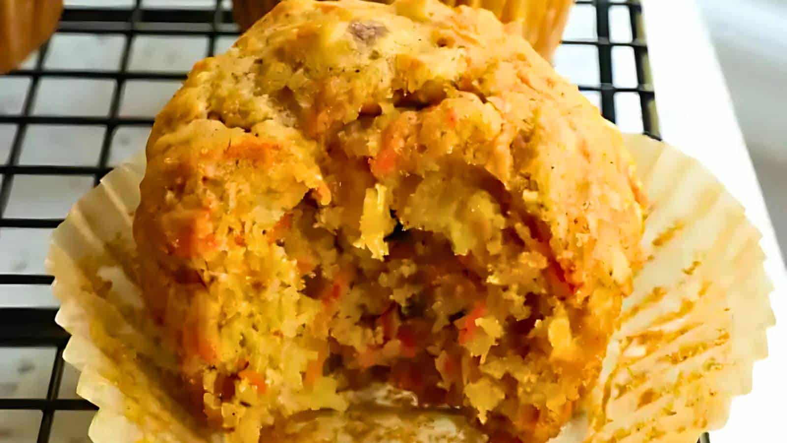 Strawberry muffin on a wooden board, surrounded by more muffins and a fresh strawberry in the background.
