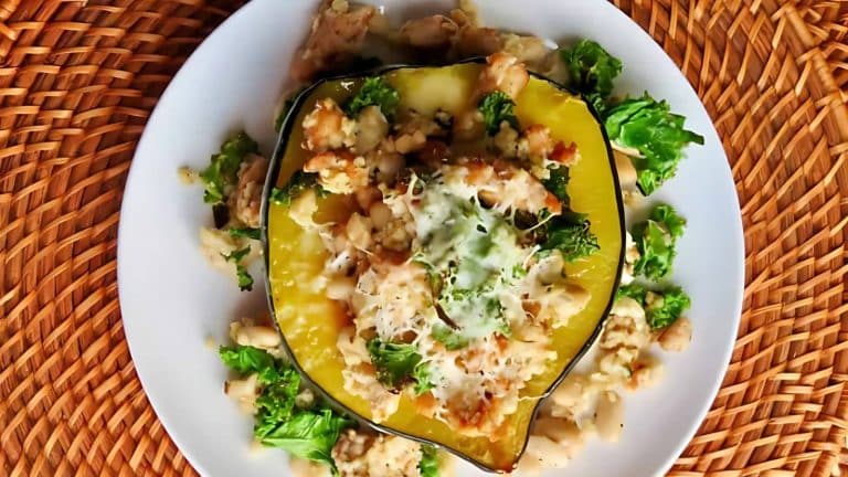 Stuffed acorn squash on a white plate with kale and cheese, set on a woven placemat.