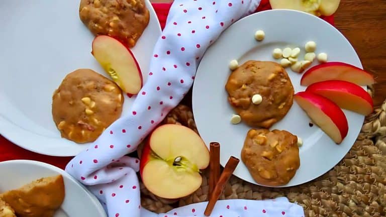 Plates with cookies, apple slices, and white chocolate chips on a polka dot napkin, surrounded by apple slices and cinnamon sticks.