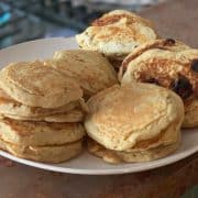A plate of homemade almond milk pancakes, some with blueberries, sits on a kitchen countertop.