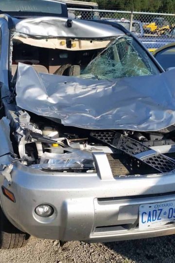 a picture of a silver suv with the front end crushed after an accident with a moose