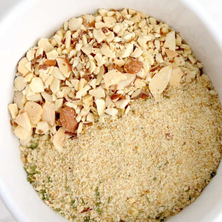 A white bowl filled with almonds and granola.