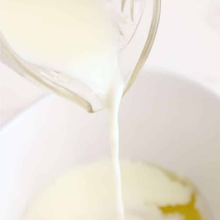A bowl of milk being poured into a bowl.