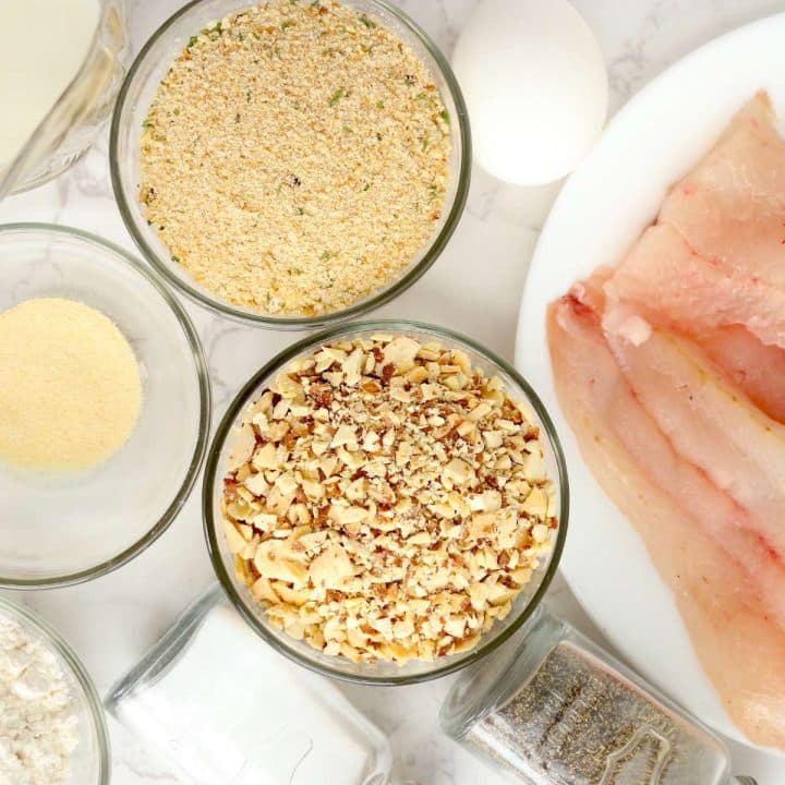 A bowl of walleye fillets, eggs, breadcrumbs and other ingredients on a white table.