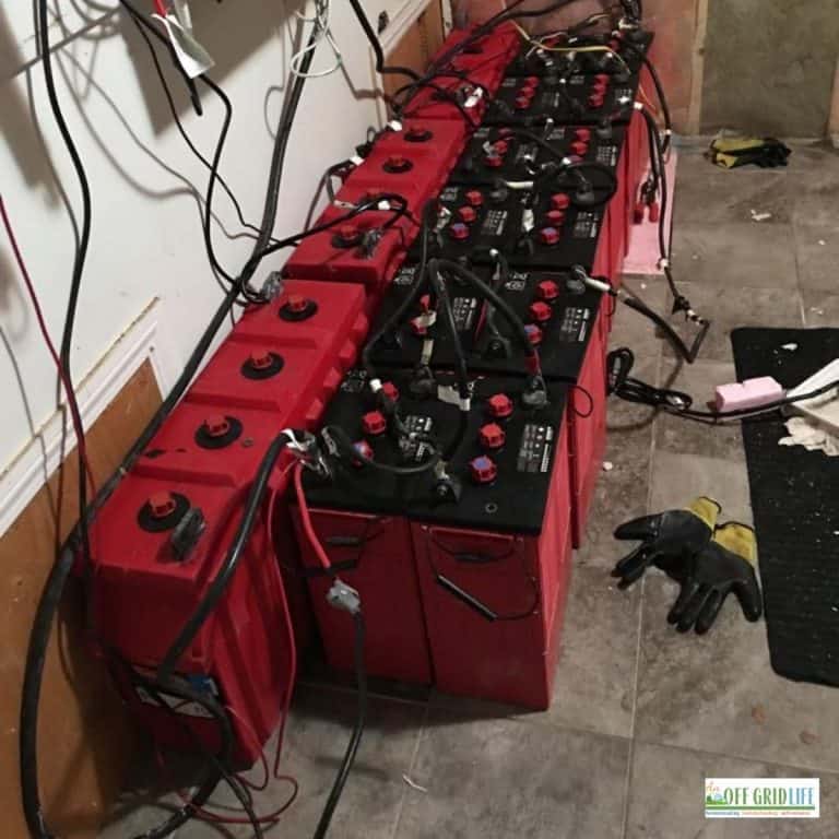a picture of a few dozen red surrette batteries connected by cables in series.