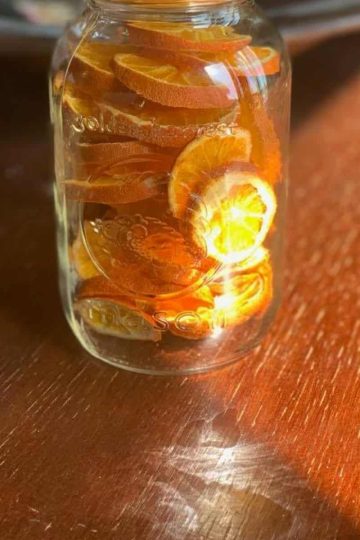 a single mason jar with dehydrated orange slices on a wooden table