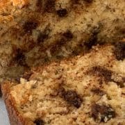 Close-up of chocolate chip banana bread on a cutting board, showing a sliced piece with visible chocolate chips and a moist, crumbly texture.