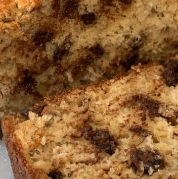 Close-up of chocolate chip banana bread on a cutting board, showing a sliced piece with visible chocolate chips and a moist, crumbly texture.
