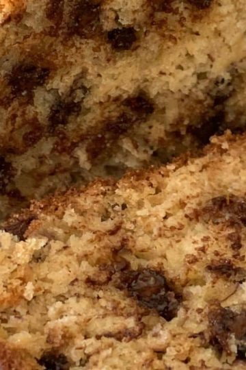Close-up of chocolate chip banana bread on a cutting board, showing a sliced piece with visible chocolate chips and a moist, crumbly texture.