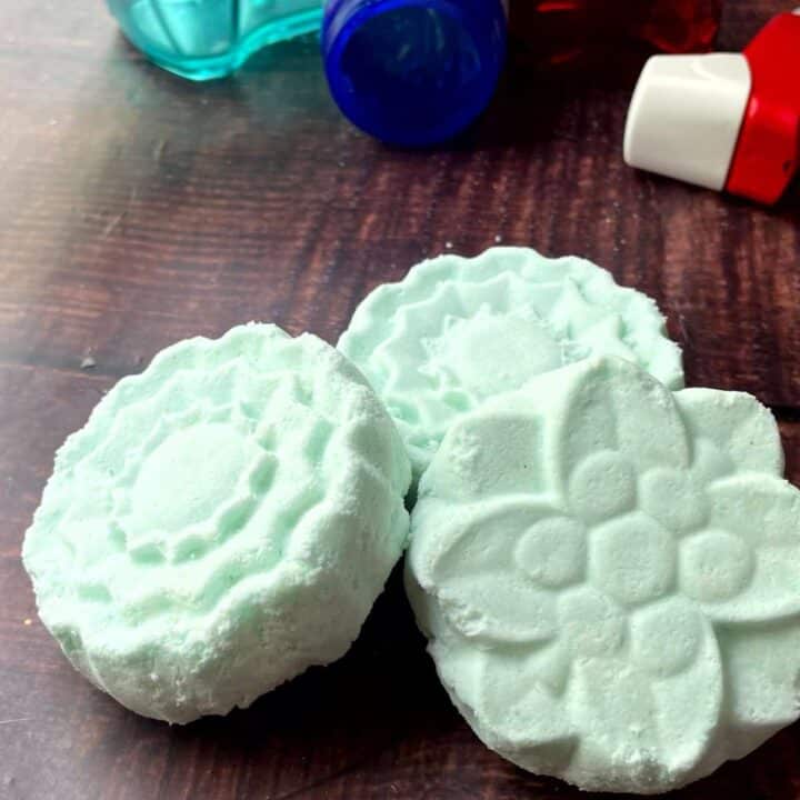 Three soaps on a table next to a bottle of soap.