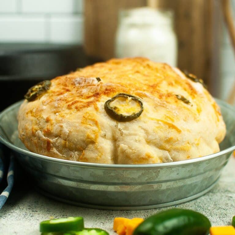 A loaf of jalapeno cheddar bread with jalapenos and jalapeno peppers.
