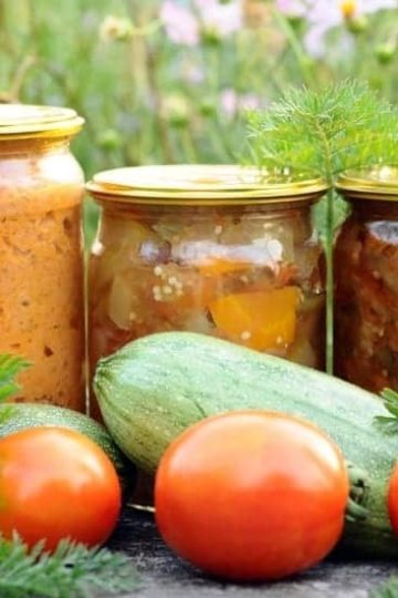 Canned vegetables in jars with fresh vegetables outdoors