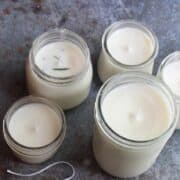 Five jars of white candles on a table.