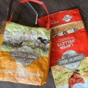 Two bags of chicken feed on a wooden floor.