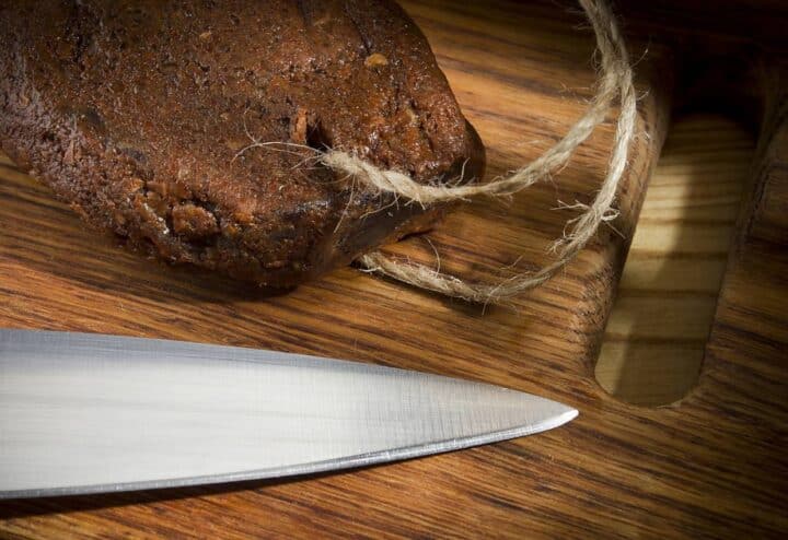 A knife on a wooden cutting board with homemade pemmican.