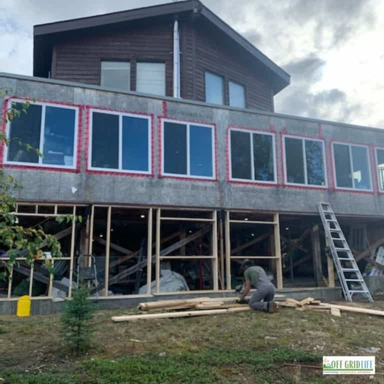 a homestead with a wrap around deck under construction and new windows being put in
