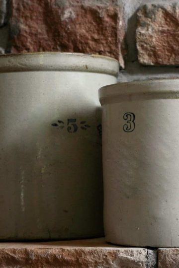 two white stone crocks with a brick wall background