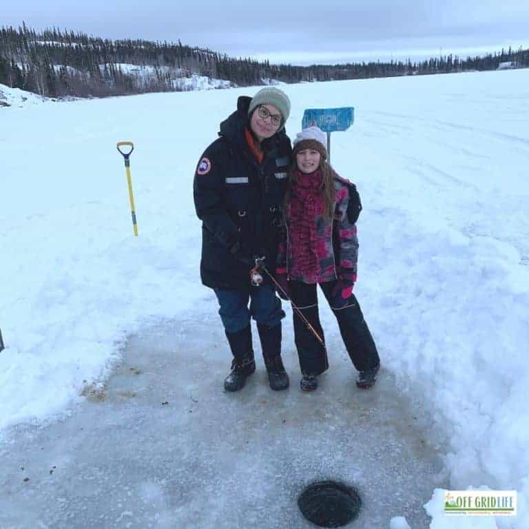 a picture of a woman and a young girl ice fishing on a frozen lake
