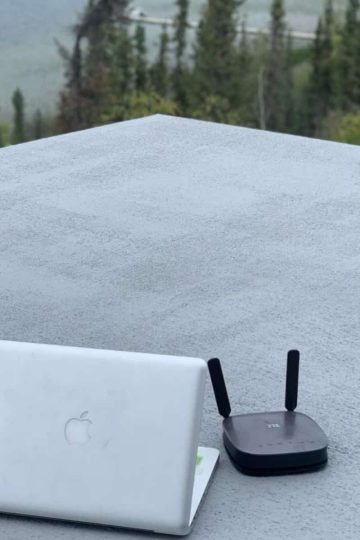 a laptop and router on a roof of an off grid cabin