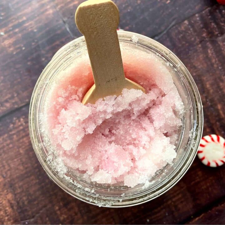 A jar of pink sugar with a wooden spoon and candy canes.