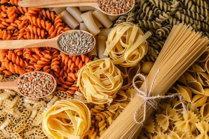Various types of pasta are arranged on top of wooden spoons.