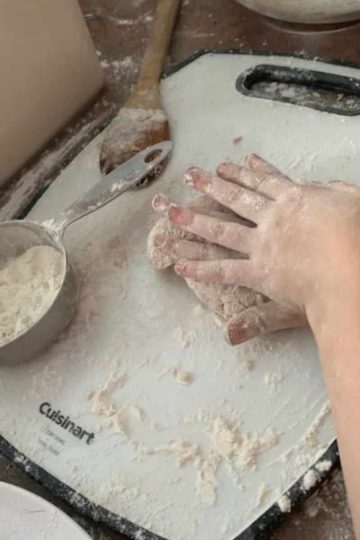 a person kneading hardtack dough on a cutting board