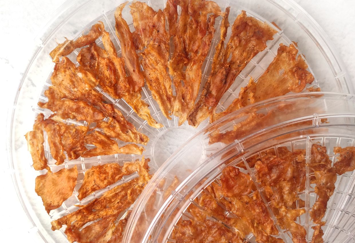 Homemade chicken jerky on dehydrator tray.
