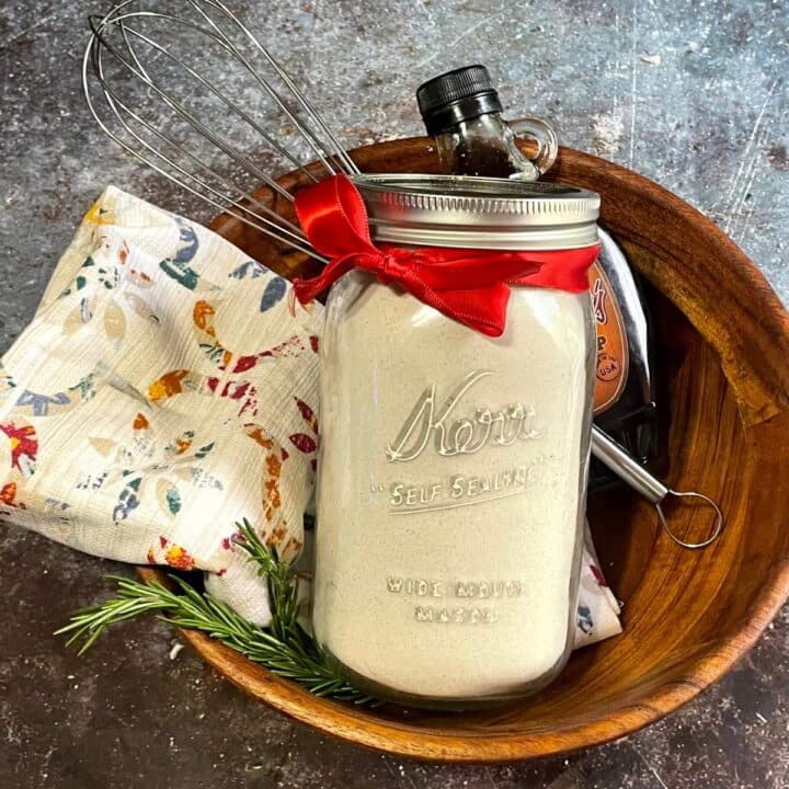 My mason jar pancake mix recipe with a whisk and utensils in a wooden bowl.