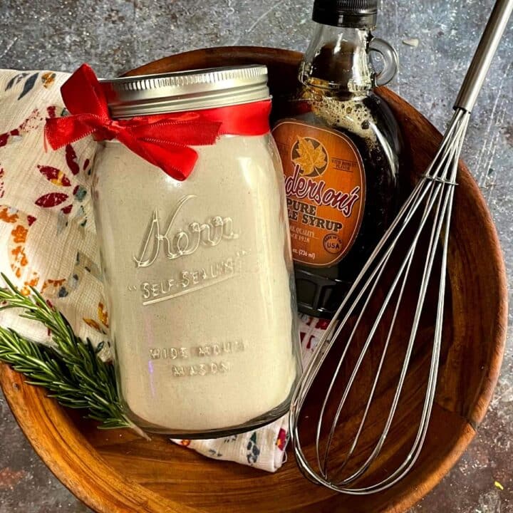 A mason jar with a whisk and a whisk in a wooden bowl.