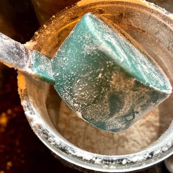 A green spatula is being used to stir flour in a bowl.