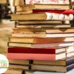An old-fashioned stack of children's Christmas books on a table near a Christmas tree.
