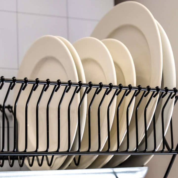 A dish rack is holding plates in a kitchen.